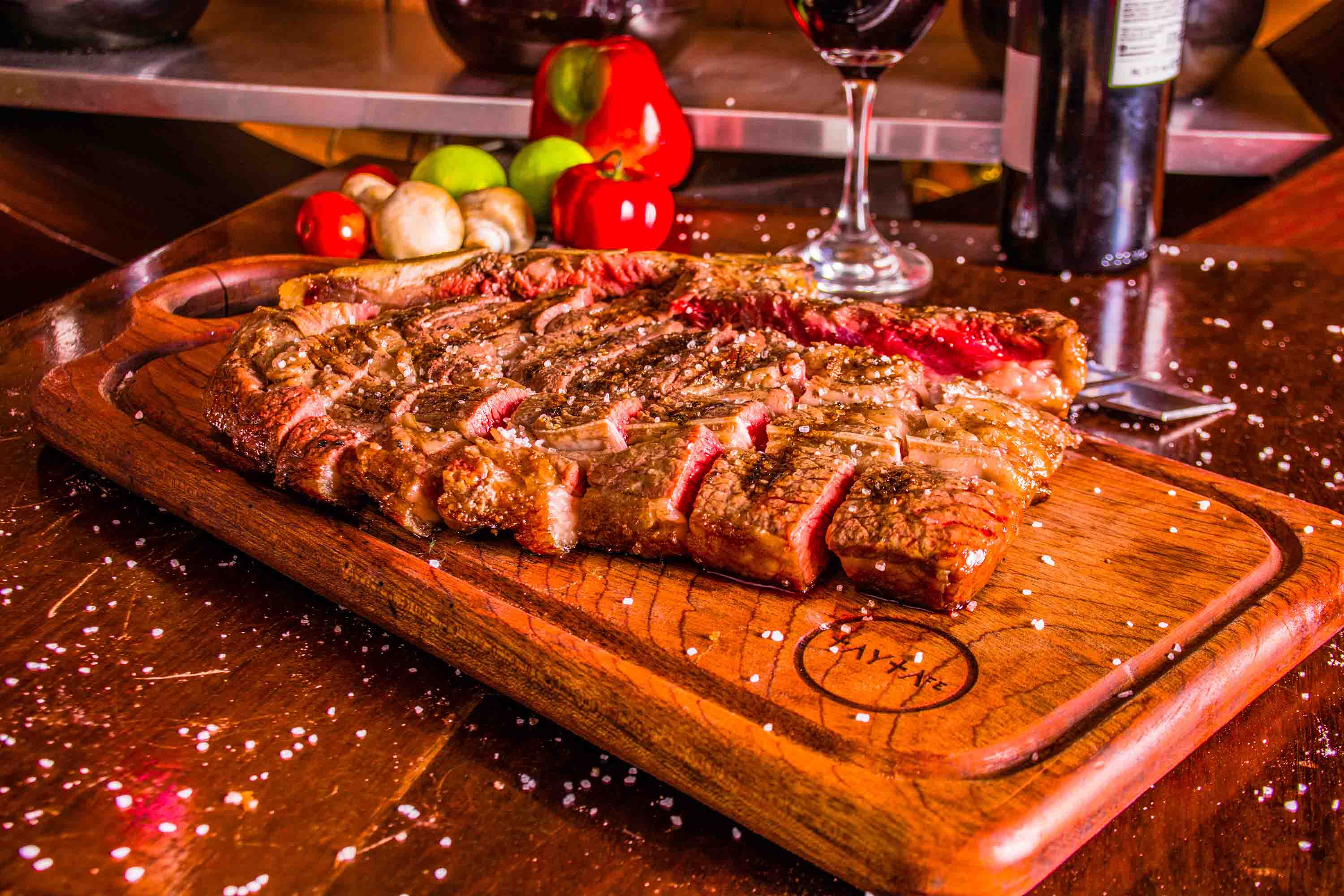 Carne grelhada servida com vinho sobre uma mesa de madeira